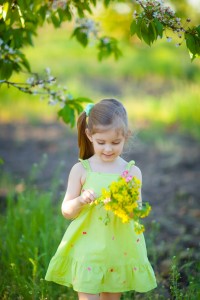 Adorable kid with bouquet of flowers in summer garden